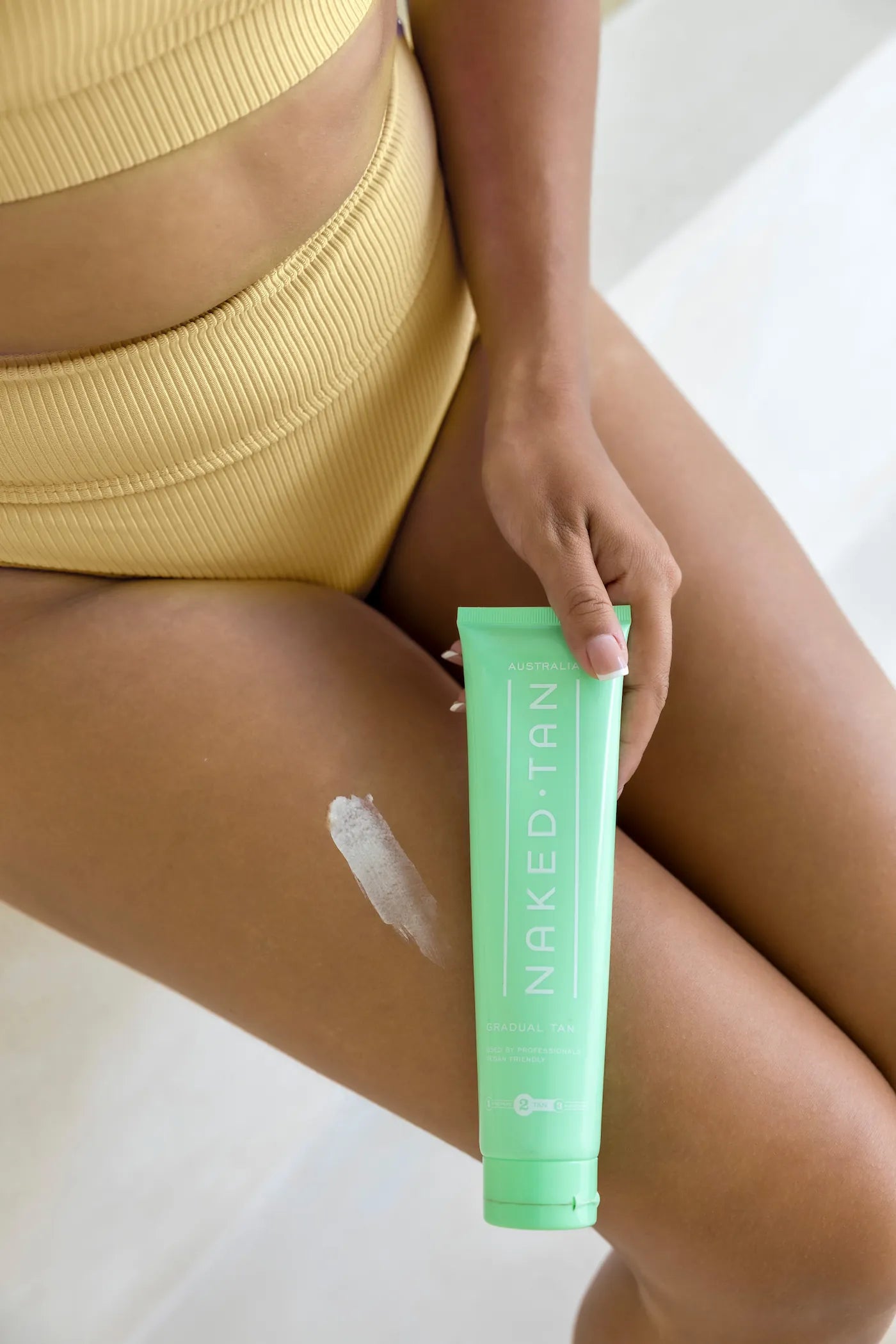 Model applying Naked Tan Gradual Tan for a subtle, buildable tan with skin-conditioning benefits